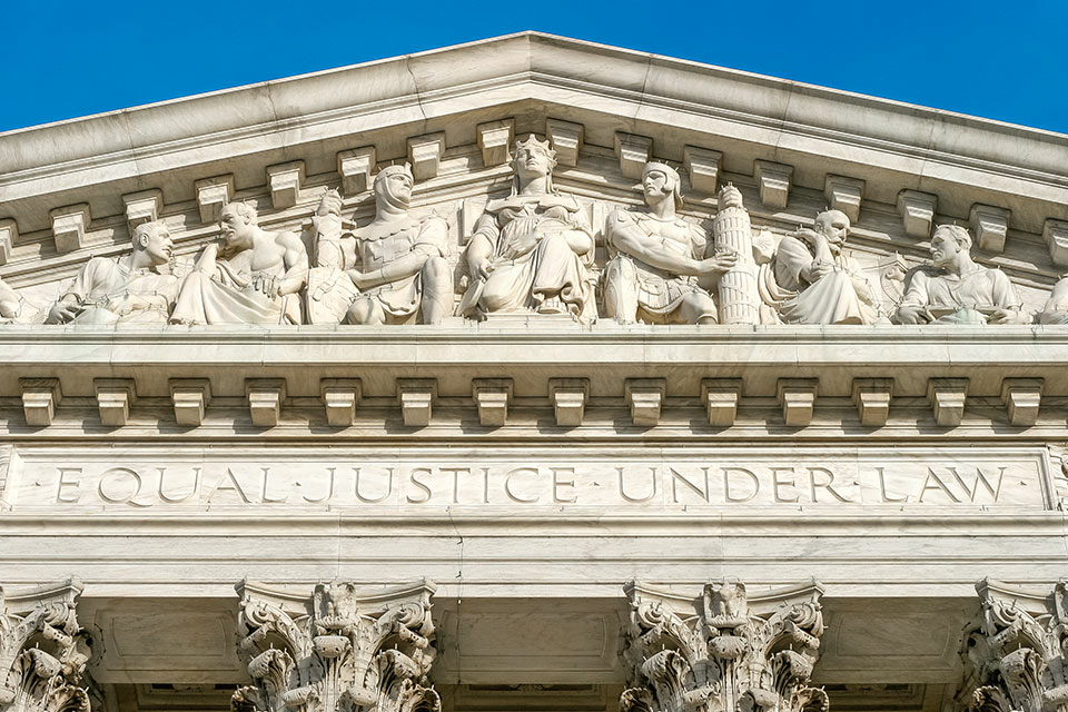 A closeup of the detail at the peak of the entrance facade of the United States Supreme Court, with the words "Equal Justice Under Law" and carvings of the justices.